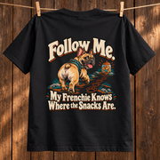 Model wearing a black French Bulldog T-shirt with the Follow Me. My Frenchie Knows Where the Snacks Are. artwork on the back