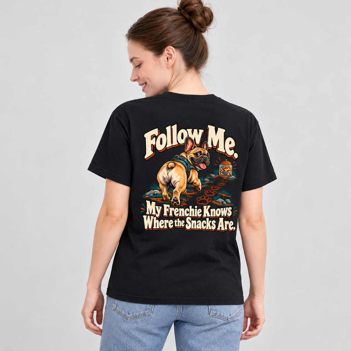 Close-up of Follow Me. My Frenchie Knows Where the Snacks Are. artwork on the back of a black cotton T-shirt
