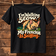 Model wearing a black French Bulldog T-shirt with the I'm Walking Slow. My Frenchie Is Sniffing. artwork on the back